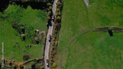 Aerial, Cinematic clip of a narrow road with earth moving trucks transporting aggregates from a quarry