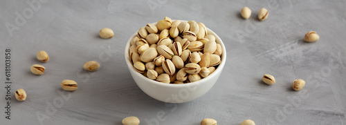Salted and Roasted Pistachios in a Bowl on a gray background, side view.