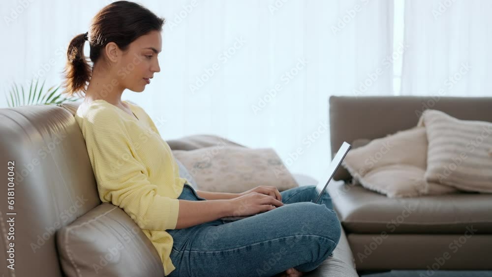 Video of beautiful young woman working with her laptop while sitting on a couch at home. Video of beautiful young woman working with her laptop while sitting on a couch at home.