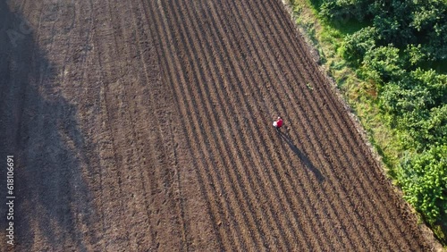 Farmer working in field before cultivation aerial view. Farmer spreading fertilizer in agricultural field aerial view.