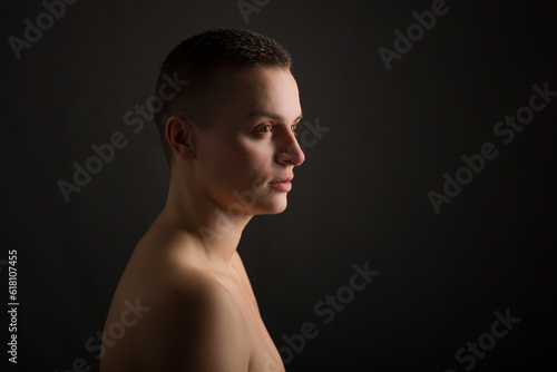 portrait of young woman with short hair and bare shoulder on black background © Igor Borodin