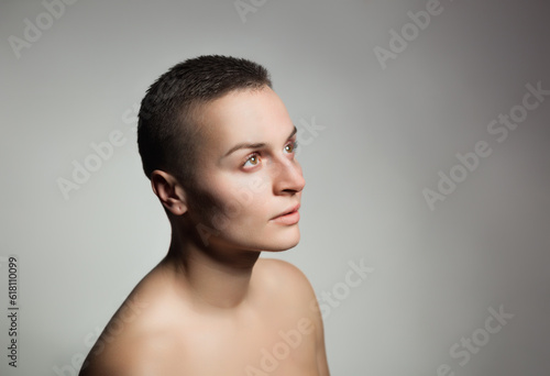 portrait of young woman with short hair and bare shoulder on grey background
