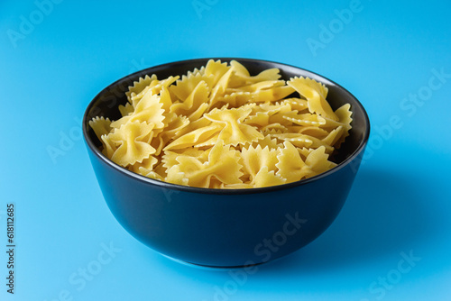 Raw pasta farfalle with copy space on blue background