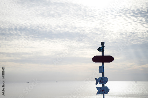 Old wooden signpost on the beach. Evening sky background, happy summer vacation concept photo