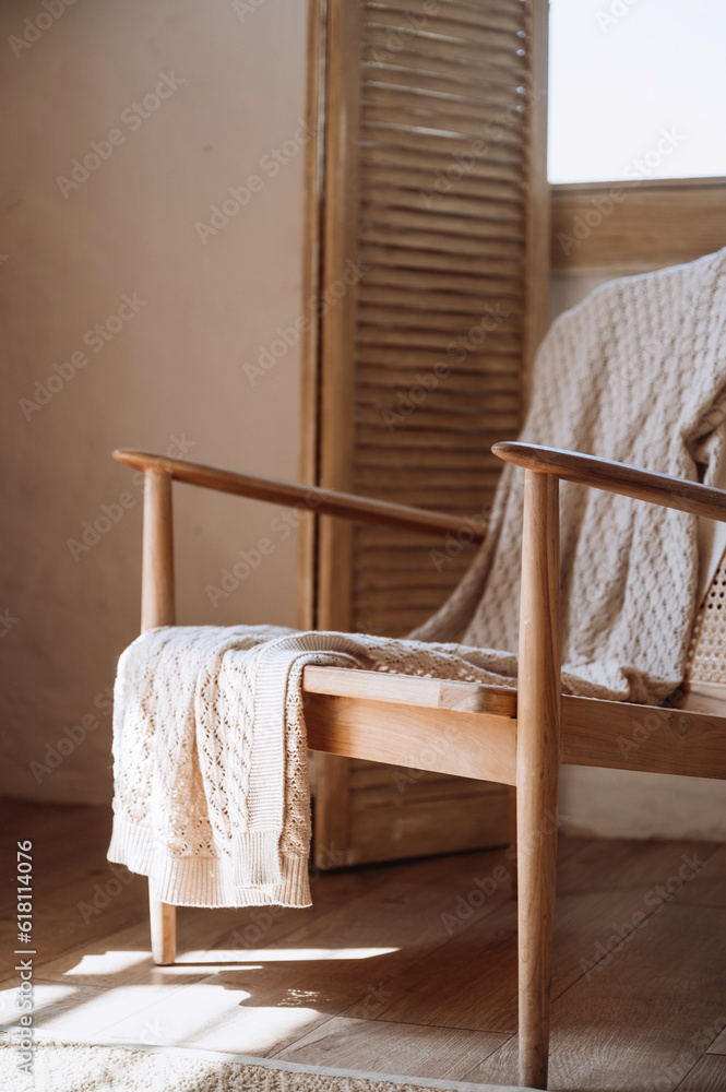 Wooden armchair with cotton knitted plaid in room Wooden armchair with cotton knitted plaid in room