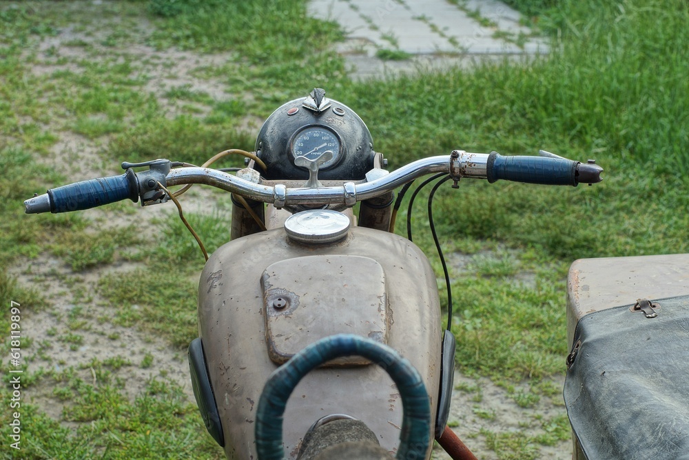 front part of old rusty classic iron with sidecar of heavy brown color retro motorcycle made in ussr on green grass outdoors in summer day front part of old rusty classic iron with sidecar of heavy brown color retro motorcycle made in ussr on green grass outdoors in summer day