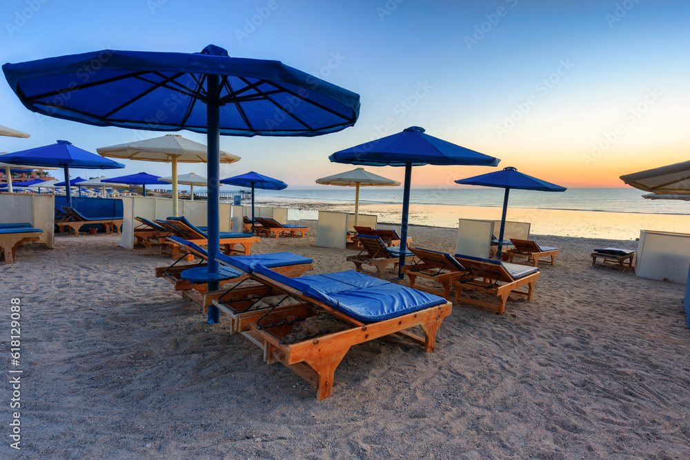 Sun loungers with umbrellas on the beach in Marsa Alam at sunrise, Egypt