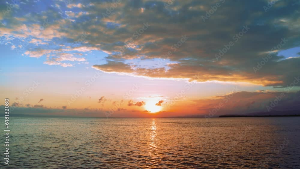 Orange sunset over the sea on a summer tropical evening. Bright sun in the blue twilight sky. Landscape sunset nature. Ripples of water with sun reflection. Colored clouds over the ocean. Orange sunset over the sea on a summer tropical evening. Bright sun in the blue twilight sky. Landscape sunset nature. Ripples of water with sun reflection. Colored clouds over the ocean.