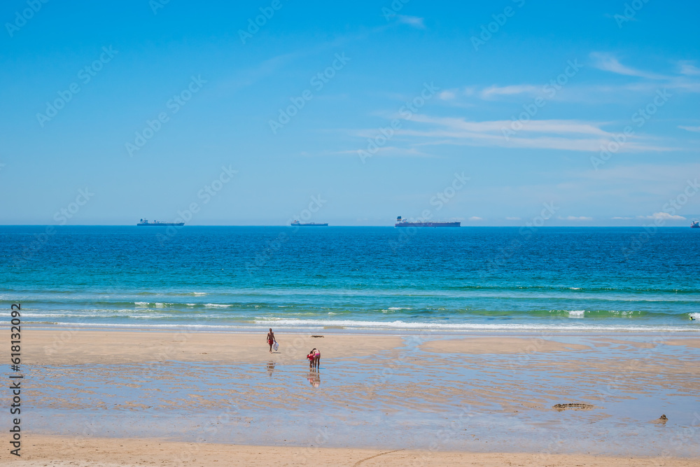 Silhouettes of people on the sand of São Torpes beach with porters in the background, Sines PORTUGAL