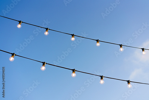 light bulbs on a wire against a blue sky, on a sunny day, lighting for a festive mood