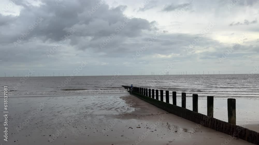 Two boys playing on wooden wave breaker poles with seagulls, English winter beach scenery Two boys playing on wooden wave breaker poles with seagulls, English winter beach scenery