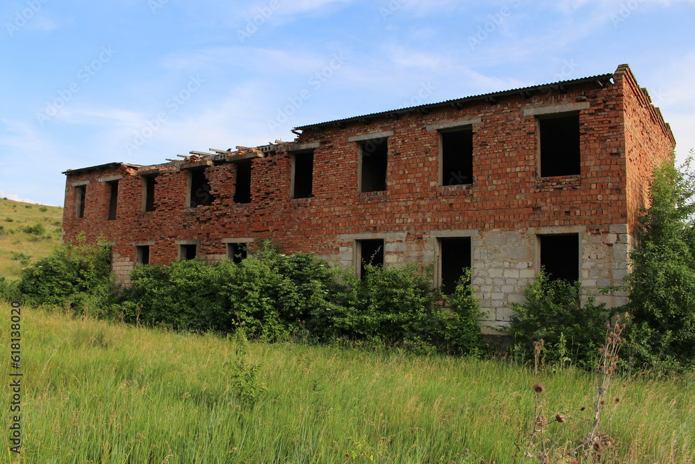 A dilapidated brick building in a grassy field