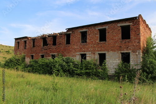 A dilapidated brick building in a grassy field