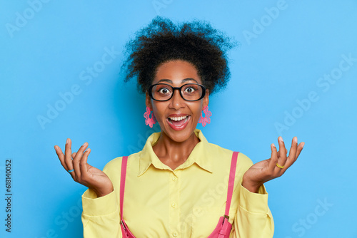 Portrait of excited african american woman in eyeglasses on blue background