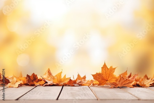 Empty wooden table with space for promotional products with yellow maple leaves and light background.