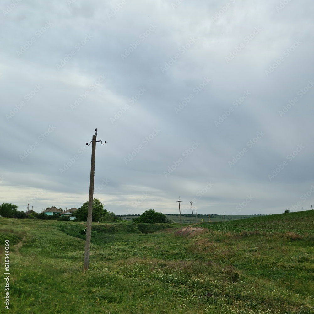 Obraz premium A field with grass and a pole with Codrington Wind Farm in the background