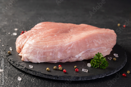 Fresh raw pork meat. A piece raw pork shoulder with spices on a slate board. Pork tenderloin. Pulpa, carne de porc. Close up.