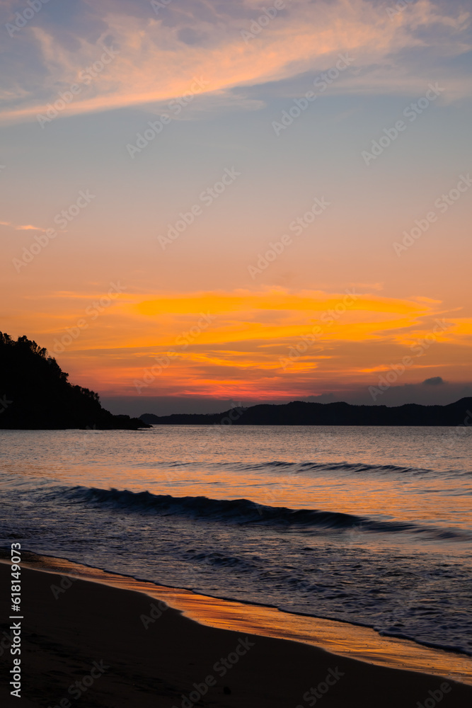Intense orange and pink sunset above the water in Duli Beach, Palawan, Philippines. Sun going down, burning sky, golden hour.
