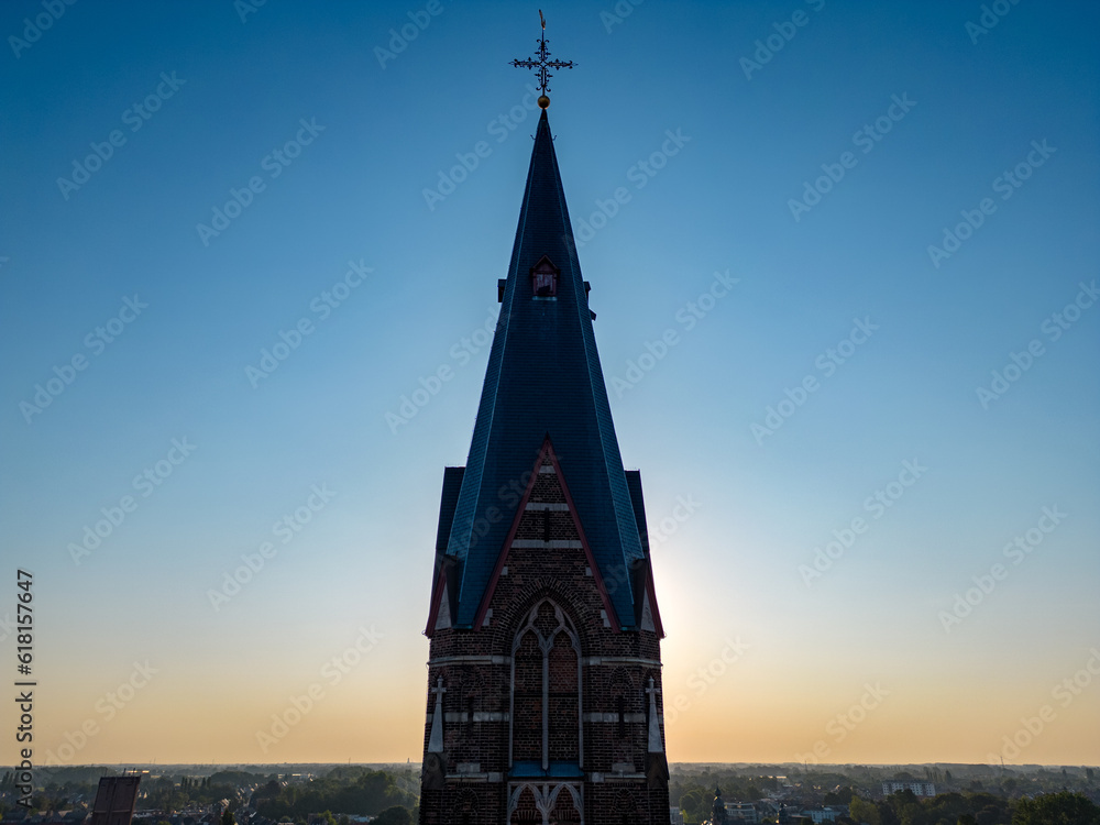 Aerial view of the silhouette of a heavenly religious church or chapel bell tower steeple against a azure blue purple sunrise sky. High quality photo
