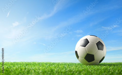 Close-up football ball on green grass with blue sky  background.