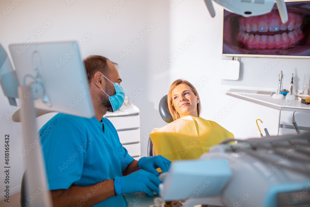 Young woman having dental work done on her teeth in a dentists office by her male dentist
