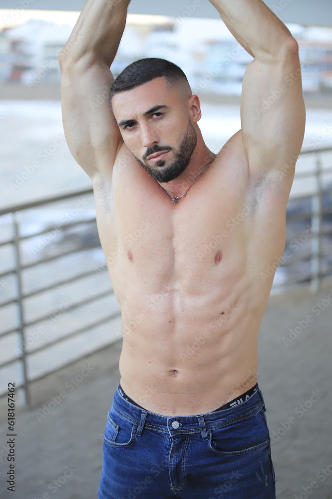 Fototapeta premium Retrato de hombre musculado posando sin camiseta con el mar de fondo. 