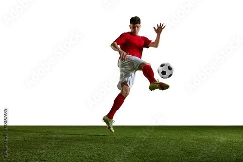 Young athletic man, football, soccer player in uniform training, kicking ball with leg against white background. Concept of professional sport, action, lifestyle, competition, hobby, training, ad © master1305
