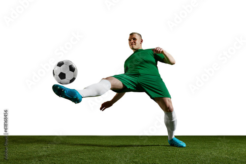 Concentrated young man, football, soccer player in uniform training, kicking ball with leg against white background. Concept of professional sport, action, lifestyle, competition, hobby, training, ad © master1305