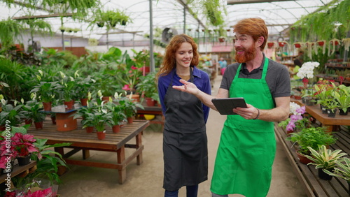Wallpaper Mural Two Staff colleagues walking through flower shop holding tablet. Happy redhaired man and woman wearing green apron inside plant local business store Torontodigital.ca