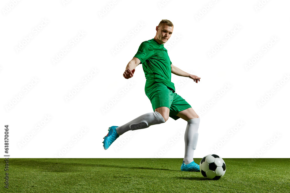 Dribbling. Young man, football player in green uniform in motion, training, playing against white background. Concept of professional sport, action, lifestyle, competition, hobby, training, ad