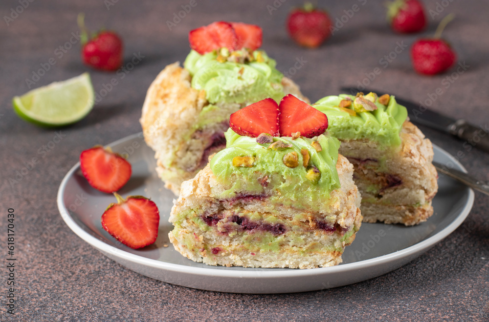 Sliced meringue roll with strawberries and pistachios on gray plate on brown background Sliced meringue roll with strawberries and pistachios on gray plate on brown background
