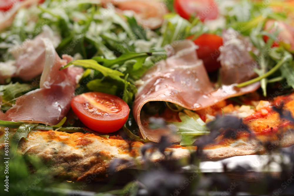 Italian pizza with cherry tomato, Italian ham, cheese and arugula, close-up, selective focus.
