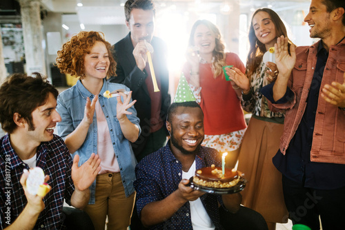 Group of young people celebrating a birthday in the office