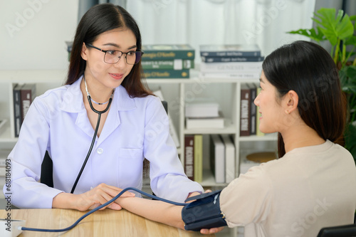 Asian female doctor measuring heart rate and blood pressure while taking care of beautiful asian patient in medical consultation in her office at clinic