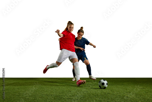Two young girls, football players in motion, training, dribbling ball against white background. Sportschool. Concept of professional sport, action, lifestyle, competition and hobby, training, ad