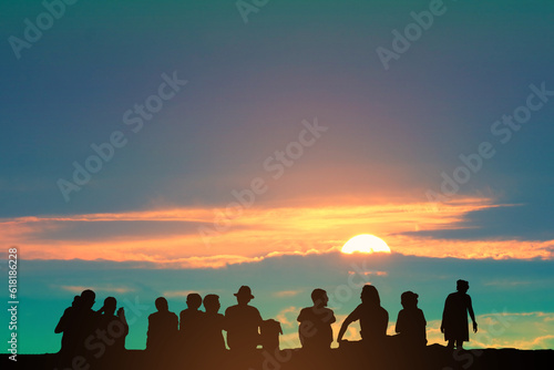 Silhouette people sitting on the floor and orange cloud sunset on the colorful sky and birds flying