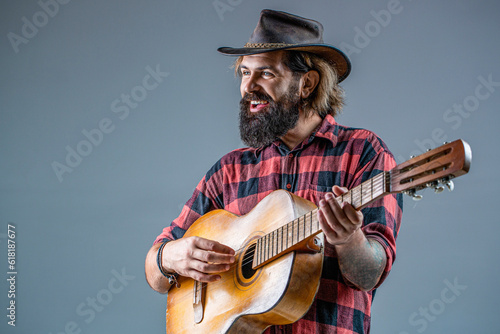 Cowboy playing guitar. Man cowboys playing acoustic guitars in wearing cowboy hat. Blues or country guitarist isolated on gray. Male in cowboys hat plays electric guitar. Old West Cowboy With Guitar