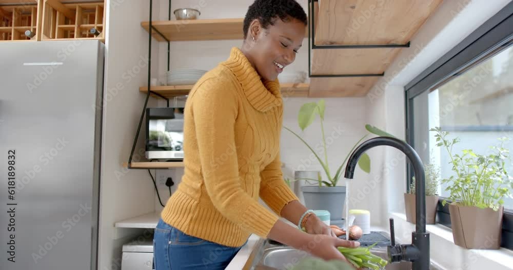 Happy african american woman rinsing vegetables in kitchen, slow motion Happy african american woman rinsing vegetables in kitchen, slow motion