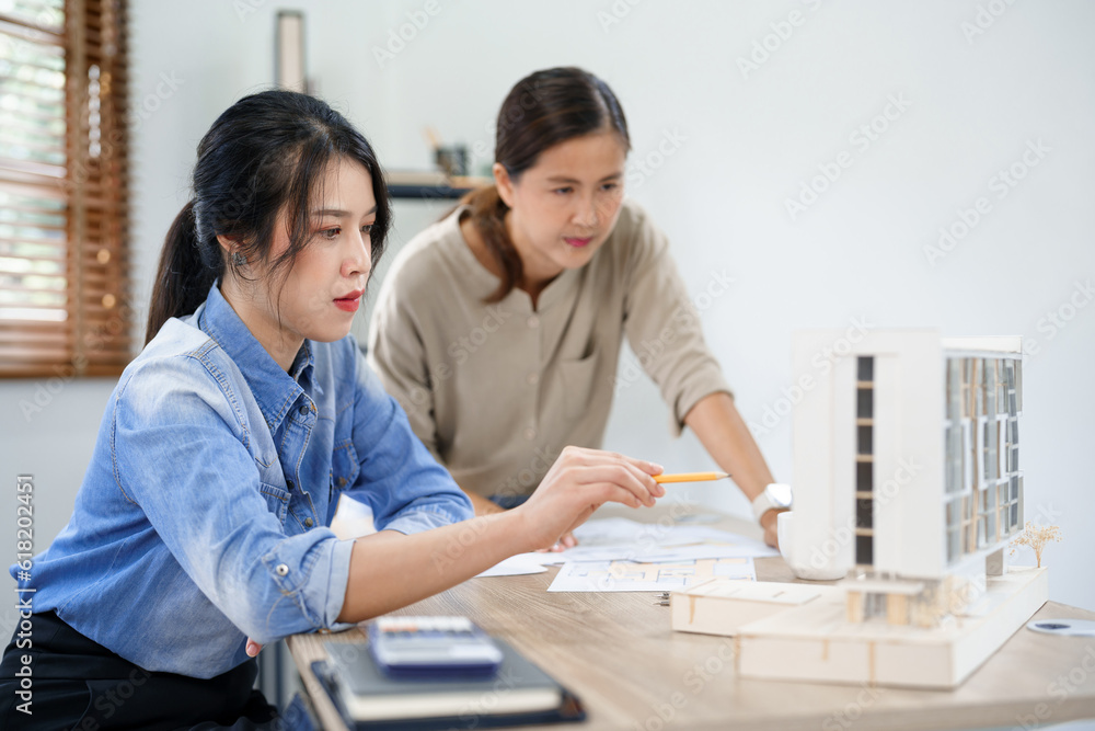 Concept of engineering consulting, Two female engineers discussing about model of building together Concept of engineering consulting, Two female engineers discussing about model of building together