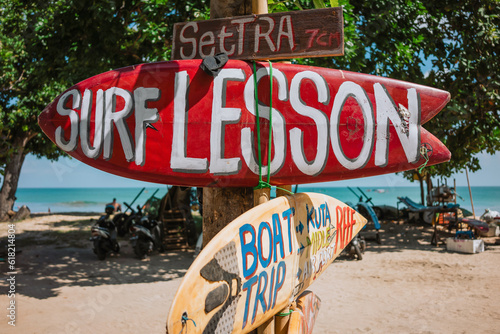 A red surfboard as a signpost with the inscription Surf lesson on Kuta beach in Bali. photo