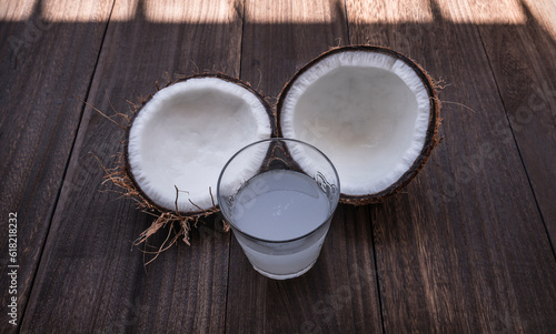 Coconut split in half and a glass of coconut water on a wooden table
