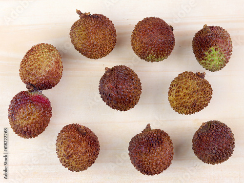 Lychee with brown skin, top view on wooden board