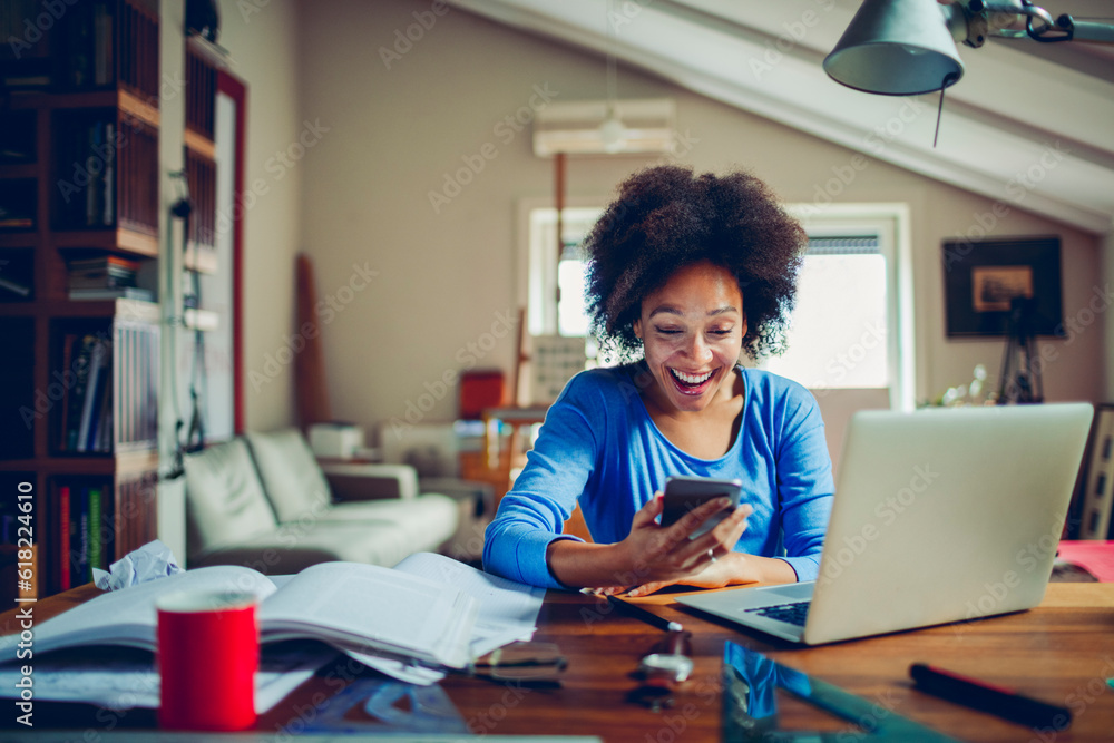 Young mixed ethnicity woman using a smart phone while studying from home Young mixed ethnicity woman using a smart phone while studying from home