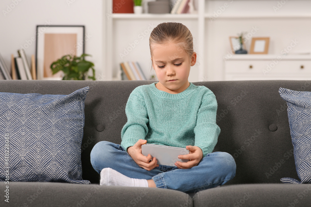 Little girl using smartphone on sofa at home. Internet addiction Little girl using smartphone on sofa at home. Internet addiction