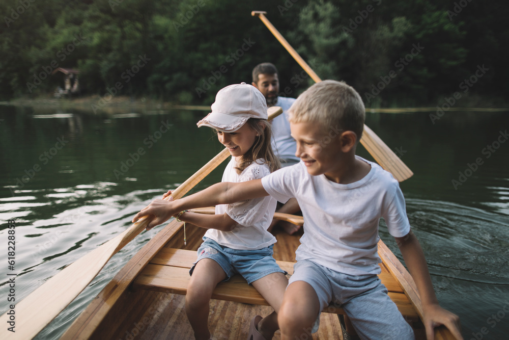 Family time, brother and sister learning to paddle canoe with father Family time, brother and sister learning to paddle canoe with father