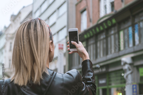 Young girl taking photo with smartphone in European city