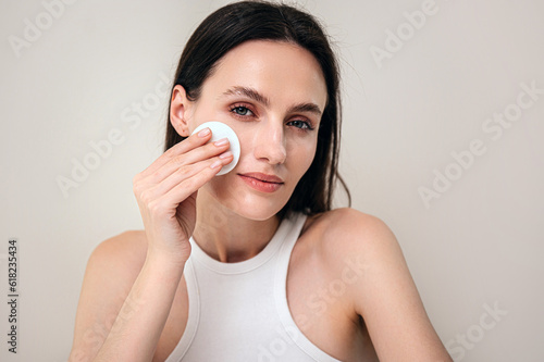 Foto portrait of woman remove makeup with cotton sponge and micellar water