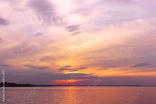 Colorful sky background on sunset, orange blue vivid color clouds and surface water on lake Ik. Nature abstract fon with reflections on water, natural shades cloudscape, nature environment