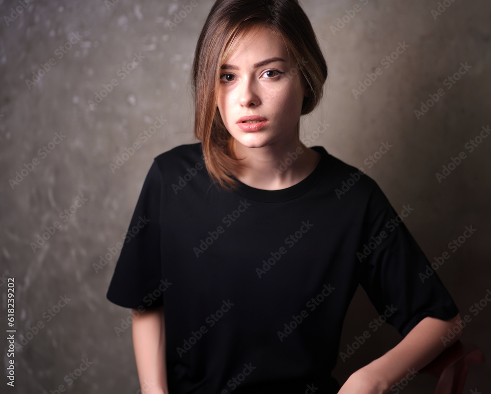 Mockup, template of a black t-shirt on a young beautiful girl on a gray background. Studio photo. Mockup, template of a black t-shirt on a young beautiful girl on a gray background. Studio photo.