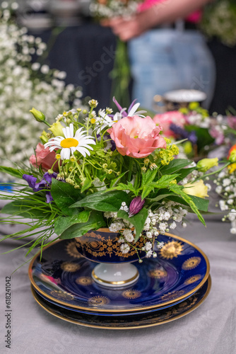 Frische Blumen arrangiert in einer alten Kaffeetasse, Blumengesteck in Vintage Geschirr, Tasse mit Blumen gefüllt, Dekoration für den Tisch